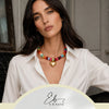A woman models a colorful flat beads necklace with a heart charm against a neutral background.