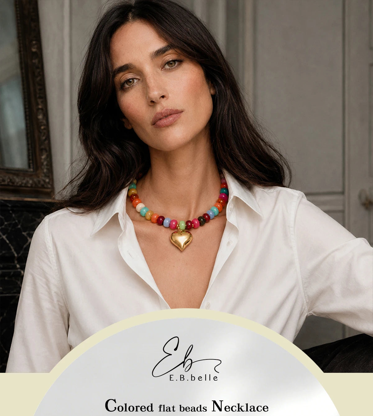 A woman models a colorful flat beads necklace with a heart charm against a neutral background.