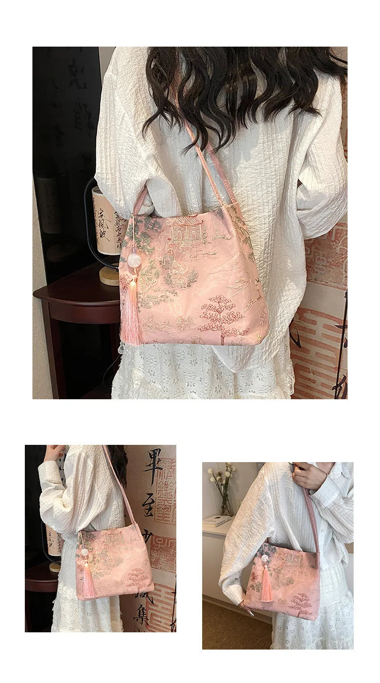 Bolso de seda jacquard rosa con borlas, sostenido por una mujer con top de encaje blanco.