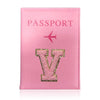 A pink leather passport holder with a gold initial V and a pink airplane symbol.