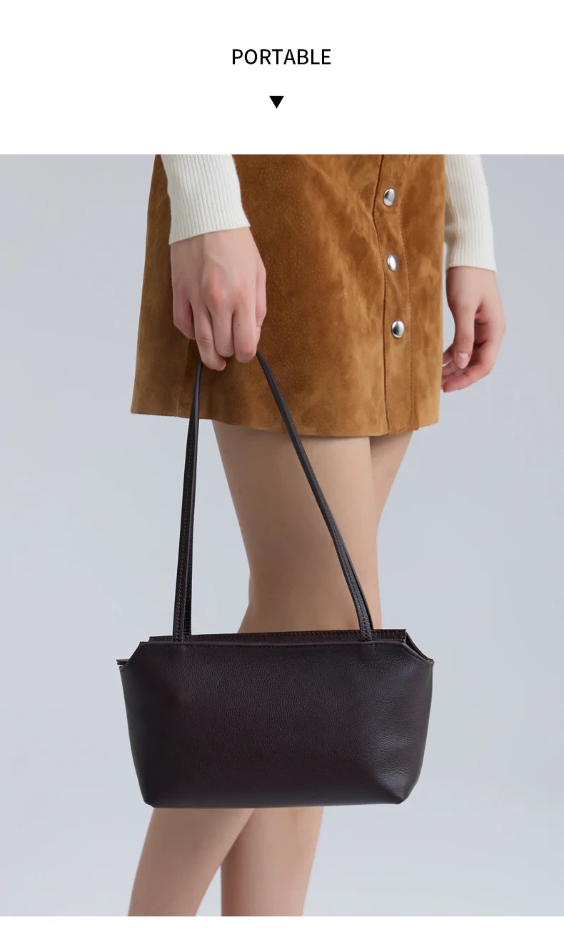 A woman is holding a dark brown leather mini shoulder bag with adjustable straps.