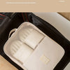 A cream-colored mesh shoe organizer bag is shown inside a black suitcase.