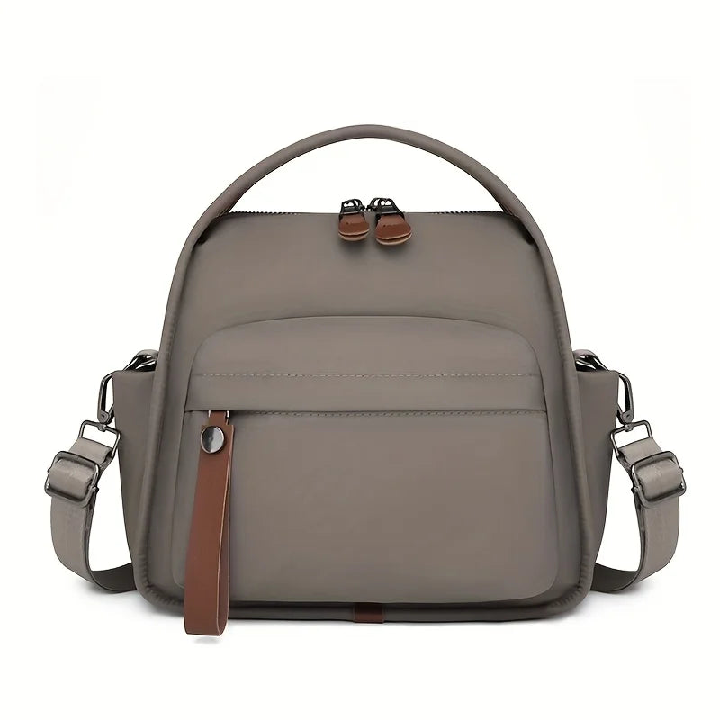 A taupe multi-pocket shoulder crossbody bag with brown leather accents.