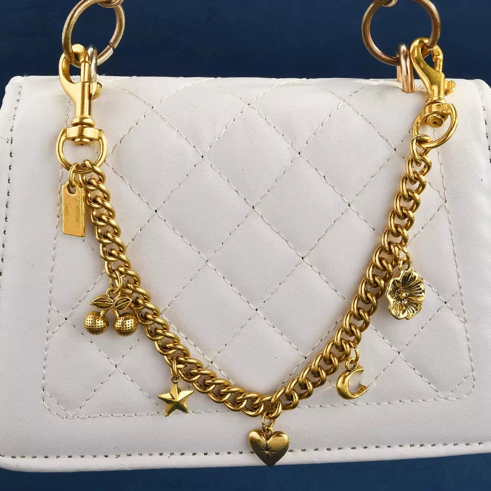 Gold chain necklace with a cherry flower pendant resting on a white quilted bag.