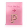 A pink leather passport holder with a gold initial P and a small airplane symbol.