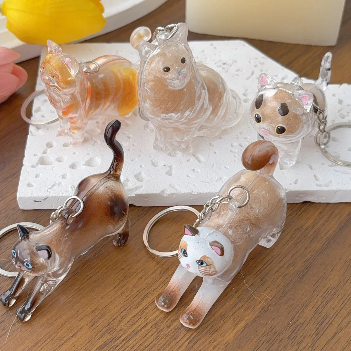A collection of transparent cat fur keepsakes and keychains resting on a white surface.