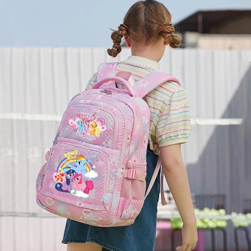 A girl is wearing a pink Oxford cloth school backpack with colorful pony designs outdoors.