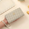 A beige patterned zipper wallet is held in a hand next to a white mesh storage tray.
