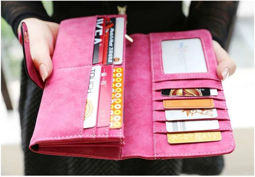 A pink PU leather clutch wallet with multiple card slots and RFID protection features is held in a hand.