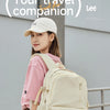 A young woman wearing a pink shirt and a white cap carries a beige Oxford school backpack outdoors.
