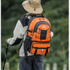 A person wearing a wide-brimmed hat and a large orange hiking backpack is standing outdoors.