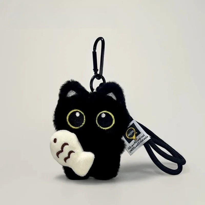 A black cat plush keychain with yellow eyes and a white paw, attached to a black cord.