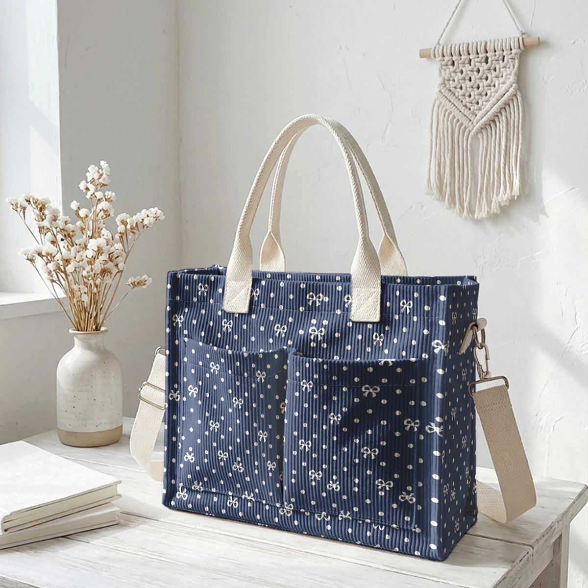 Sac en corduroy bleu marine à pois blancs et anses beige clair sur une surface en bois blanc.