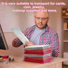 A man is handling a stack of red and green holographic bubble mailers on a wooden table.