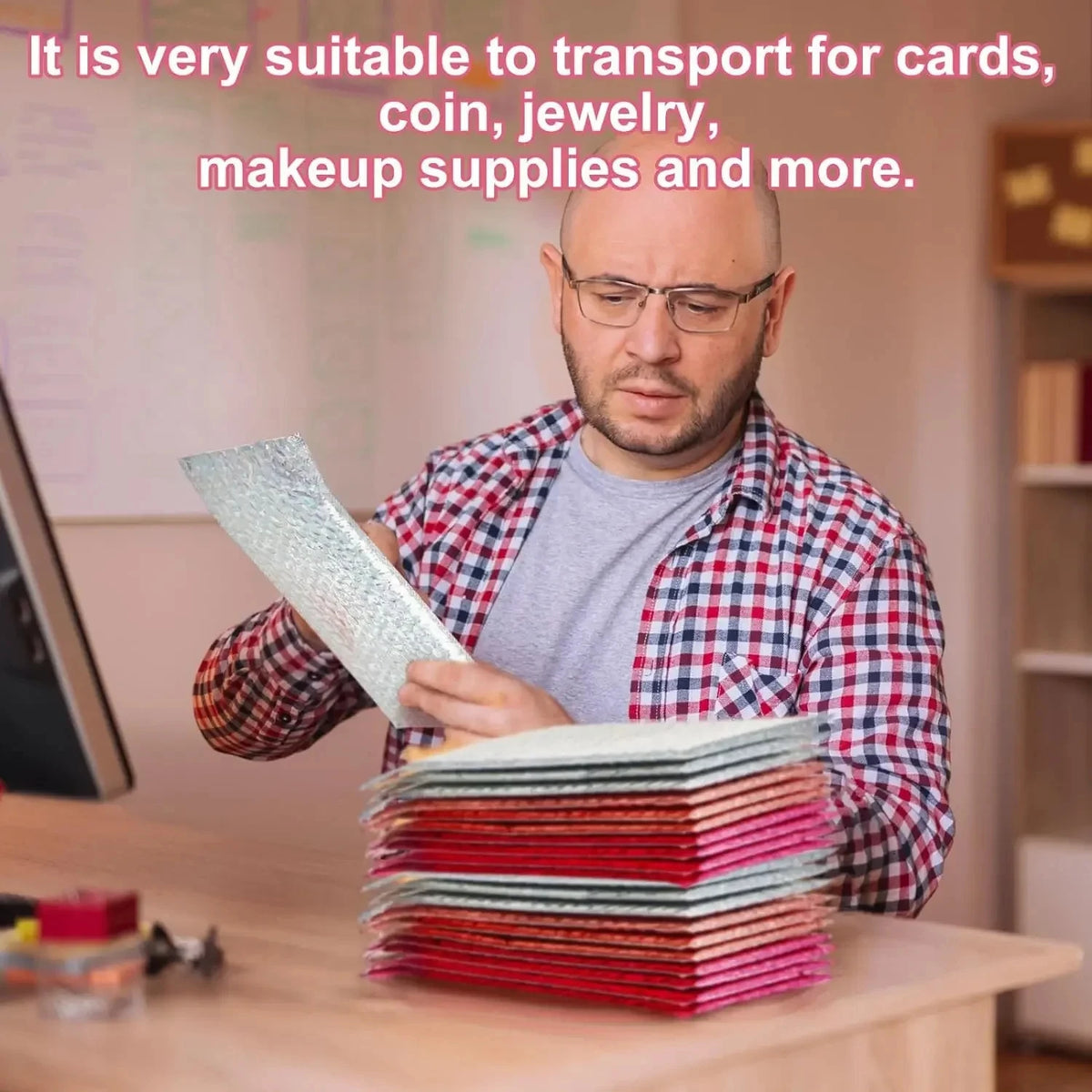 A man is handling a stack of red and green holographic bubble mailers on a wooden table.
