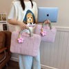 A person holds a pink quilted laptop sleeve with pink flowers and a light blue laptop.