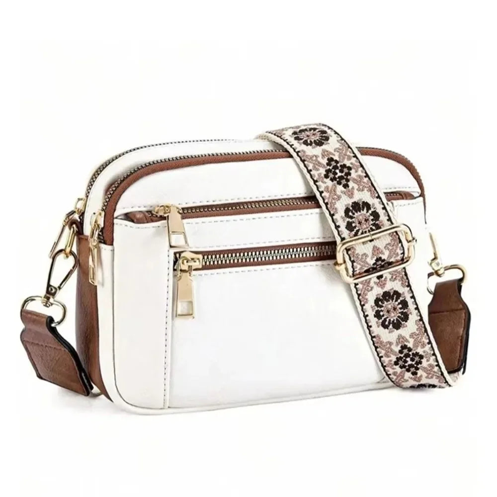 A white and brown patterned PU leather crossbody bag with gold hardware.