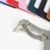 A close-up view of a set of custom PU leather luggage tags in various pastel and dark colors, showing the metal clip detail.