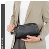 Un homme tient un sac clutch en cuir PU noir avec une sangle devant un blazer beige clair.