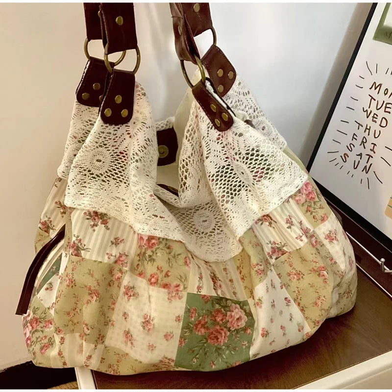 A bohemian floral patchwork shoulder bag featuring white lace and patterned fabric in pinks, greens, and creams.