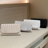 A display of several white and beige luxury chain shoulder clutch bags on a light-colored surface.
