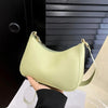 A light lime green PU leather shoulder bag with a gold zipper and strap is held against a black background.
