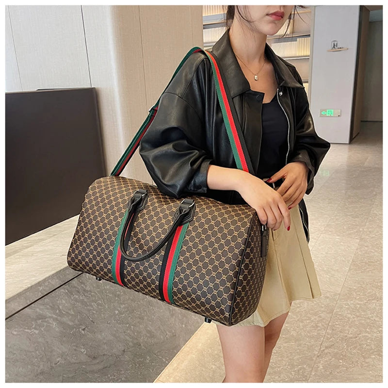 A woman is holding a brown plaid travel duffle bag and wearing a black leather jacket.