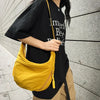 A woman wearing a black t-shirt and khaki shorts holds a yellow soft nylon crossbody bag.