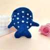 A dark blue shark mini plush toy with white polka dots resting on a light surface.