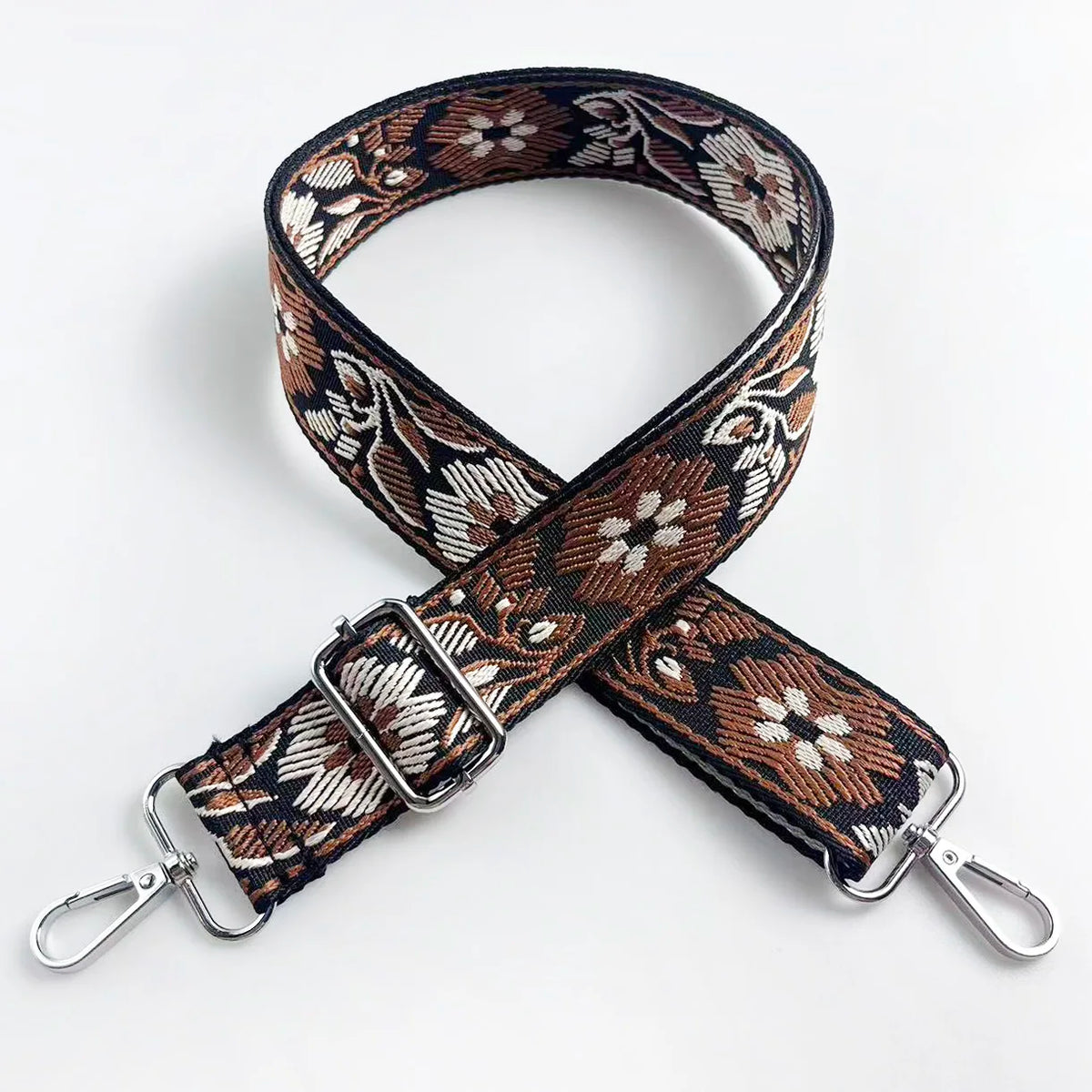 A close-up of a brown and cream patterned fabric strap for an adjustable crossbody bag.