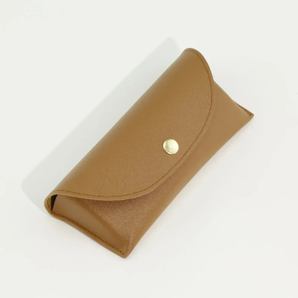 A tan PU leather hard shell sunglasses case lying on a white surface.
