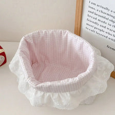 Cesta de almacenamiento de tela de costura blanca y rosa a rayas sobre una superficie blanca.