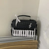 Black and white piano print crossbody bag with white keys and a white ribbon