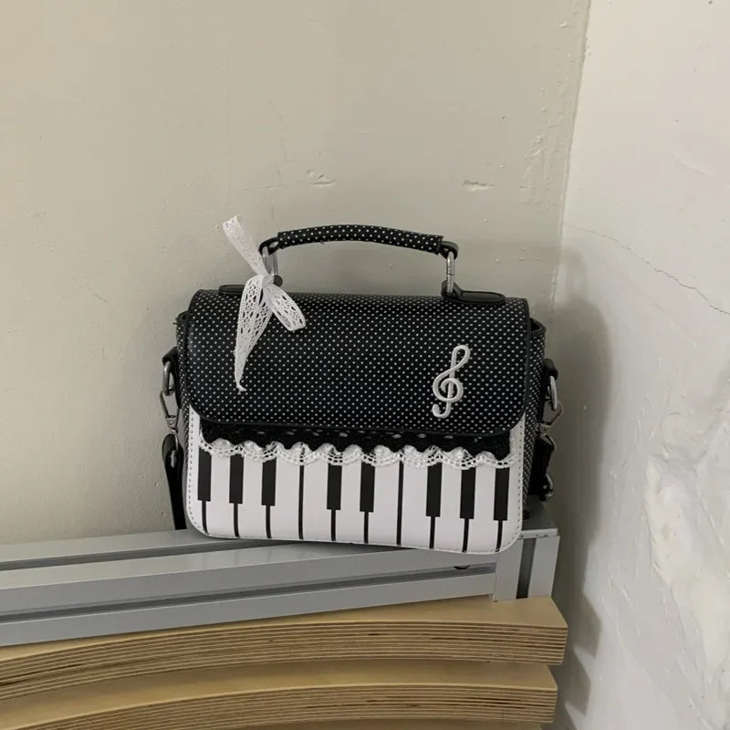 Black and white piano print crossbody bag with white keys and a white ribbon