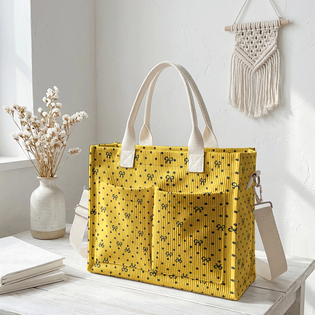 Sac en corduroy jaune à pois roses, exposé sur une surface blanche avec des fleurs séchées.