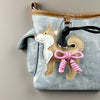 Bolsa de mezclilla azul claro con un charm de perro Shiba Inu color canela y un lazo de cuero trenzado rosa.