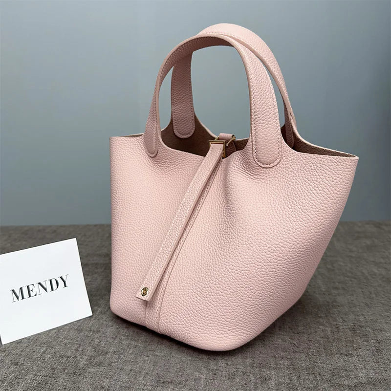 A light pink classic genuine leather bucket bag with a drawstring closure is displayed on a gray surface.