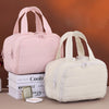A pink cosmetic organizer bag and a cream-colored cosmetic organizer bag are shown next to a stack of books.