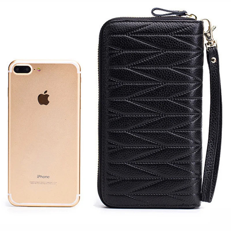 Black genuine leather RFID women's travel wallet with zipper closure next to an iPhone.