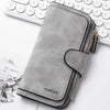 A grey leather zippered wallet with a flap is shown next to a white laptop keyboard.