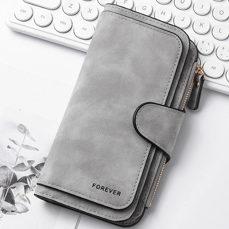 A grey leather zippered wallet with a flap is shown next to a white laptop keyboard.