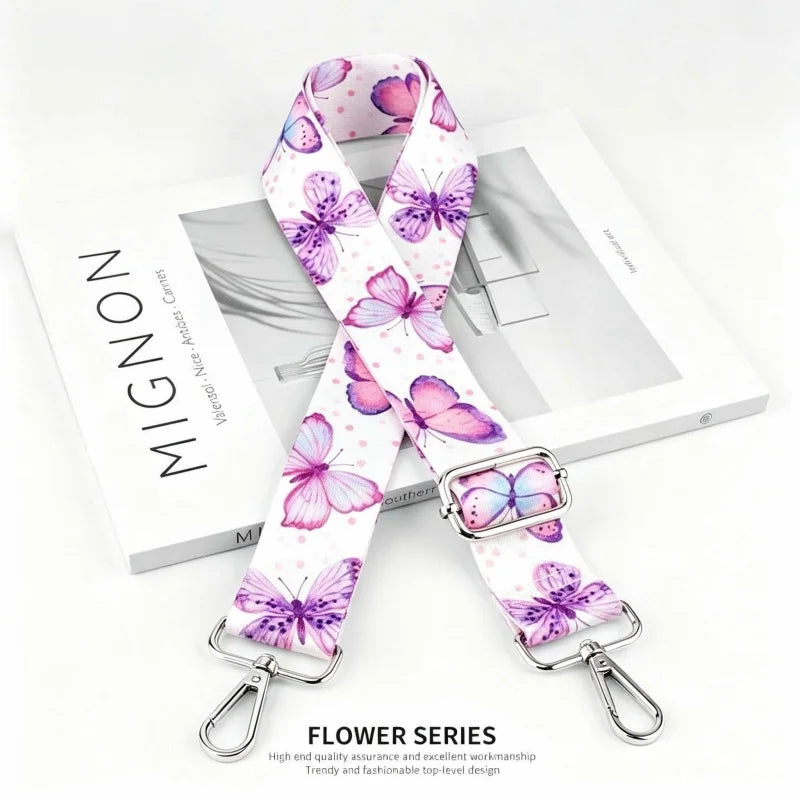 A pink and purple floral patterned nylon strap for bags and purses.
