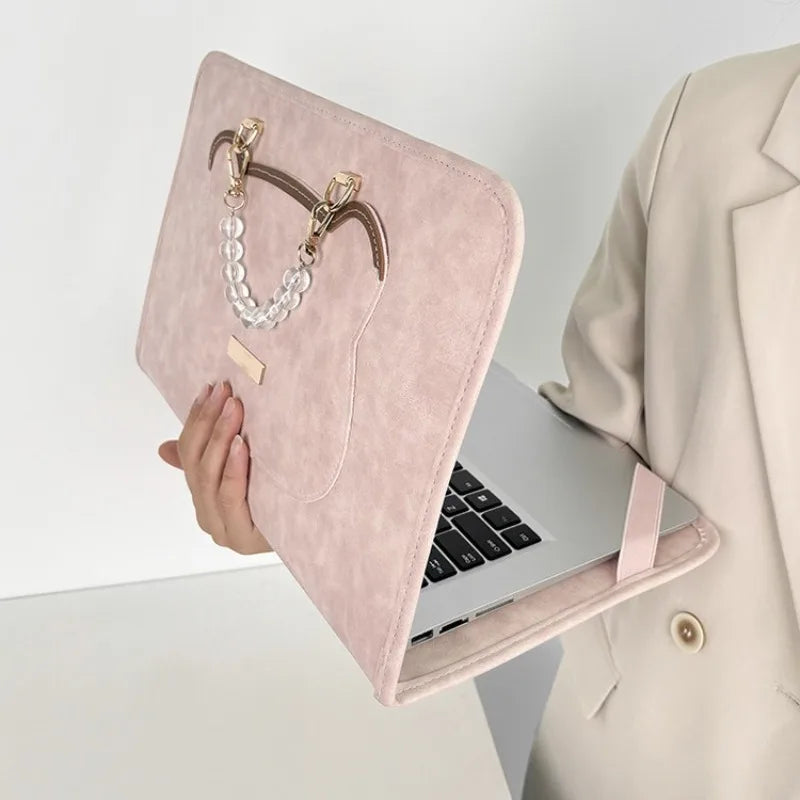 A pink PU laptop sleeve with a gold chain charm is shown next to an open silver laptop.