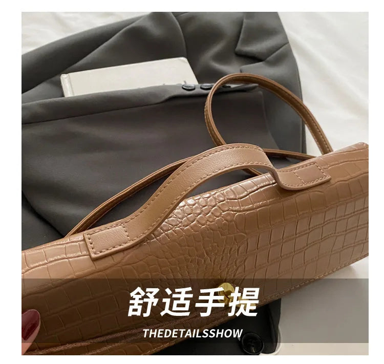 A tan crocodile-embossed PU leather clutch bag is shown resting on a gray blazer.