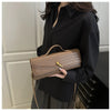 A woman holds a tan crocodile-embossed PU leather clutch bag against a black shirt.