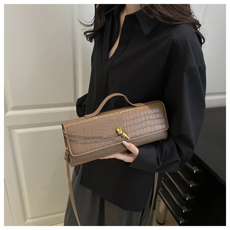 A woman holds a tan crocodile-embossed PU leather clutch bag against a black shirt.