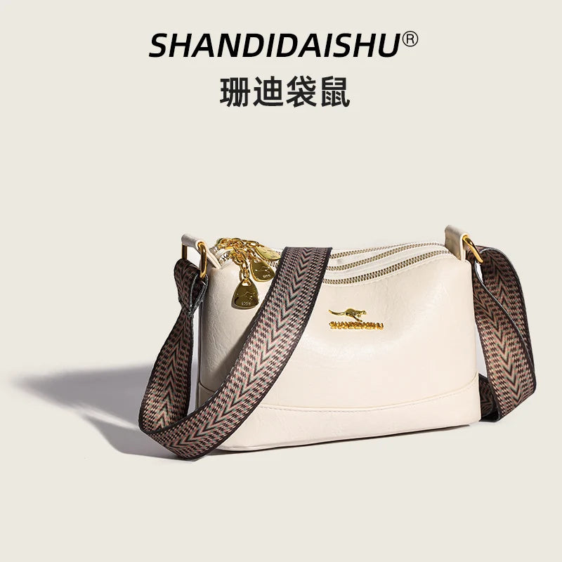 A beige luxury PU leather crossbody handbag with gold hardware and a patterned strap.