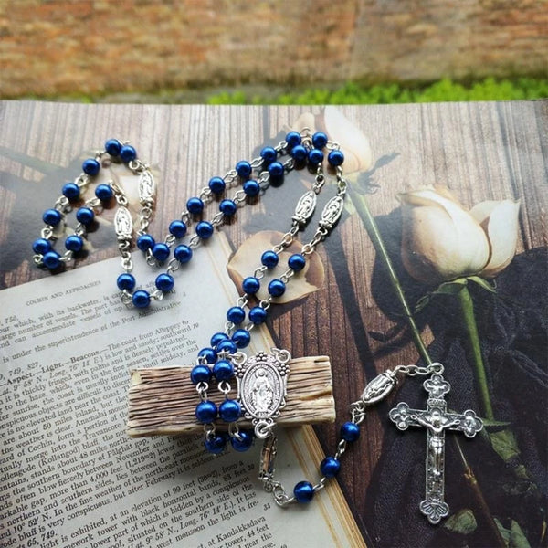 A blue rosary necklace with a silver cross pendant resting on a wooden surface.