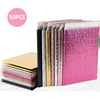 A stack of 50 holographic bubble mailers in various colors and finishes, including pink and gold.