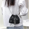Bolso cruz de cordón brillante negro con pedrería, usado por una persona con camisa blanca.